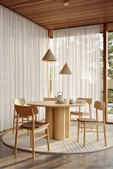 Natural oak wooden round dining table styled in modern dining room