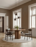 Walnut round wooden dining table styled in modern dining space